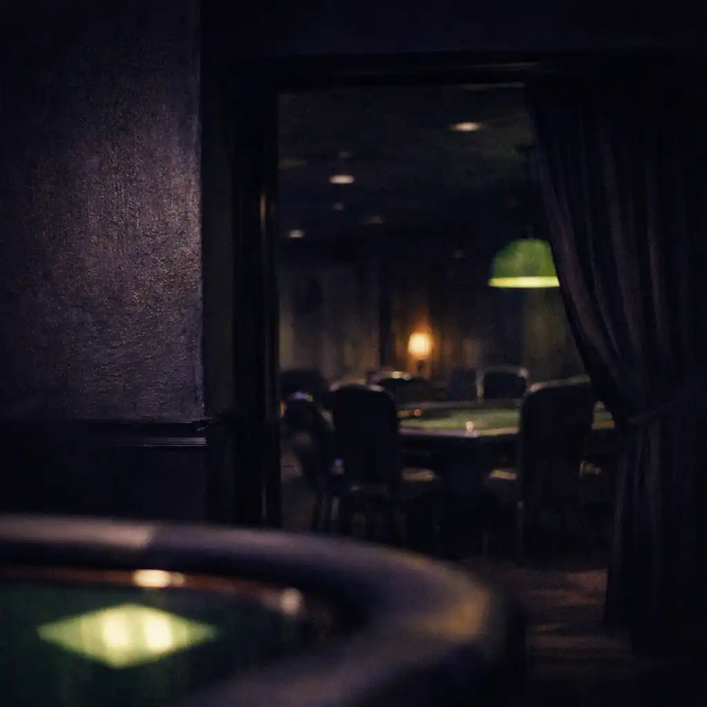Dim card lounge threshold with a poker-table edge in the foreground